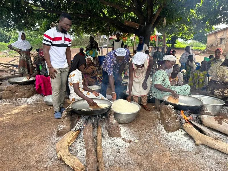 Women processing produce together over open cooking pans