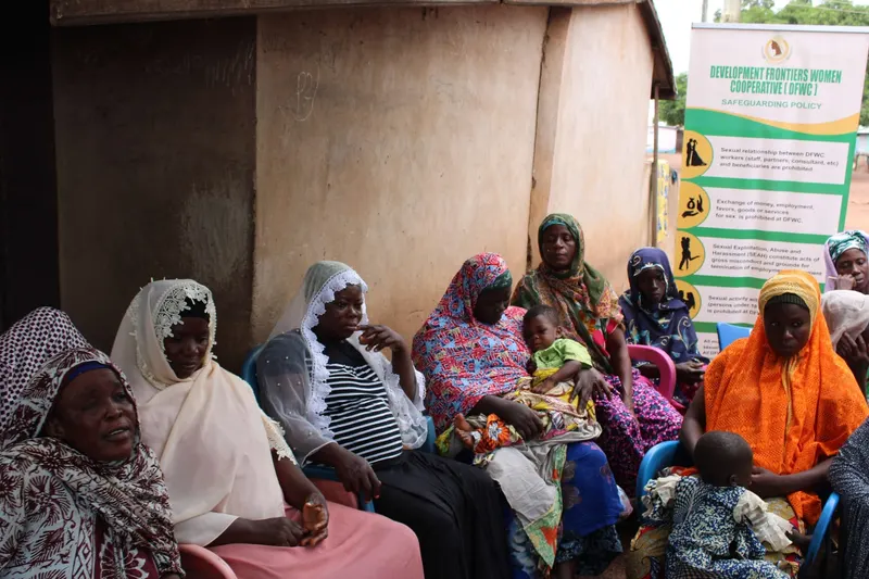 Women seated at a community meeting in front of DFWC banners
